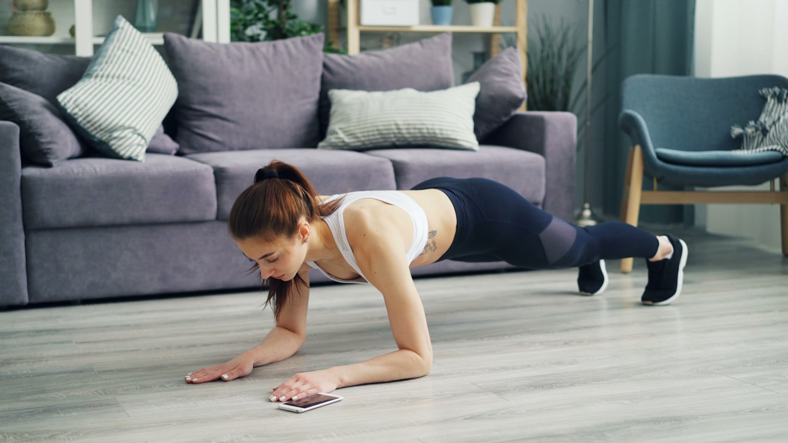 Vrouw die thuis push-ups doet op een yogamat - thuistraining voor beginners